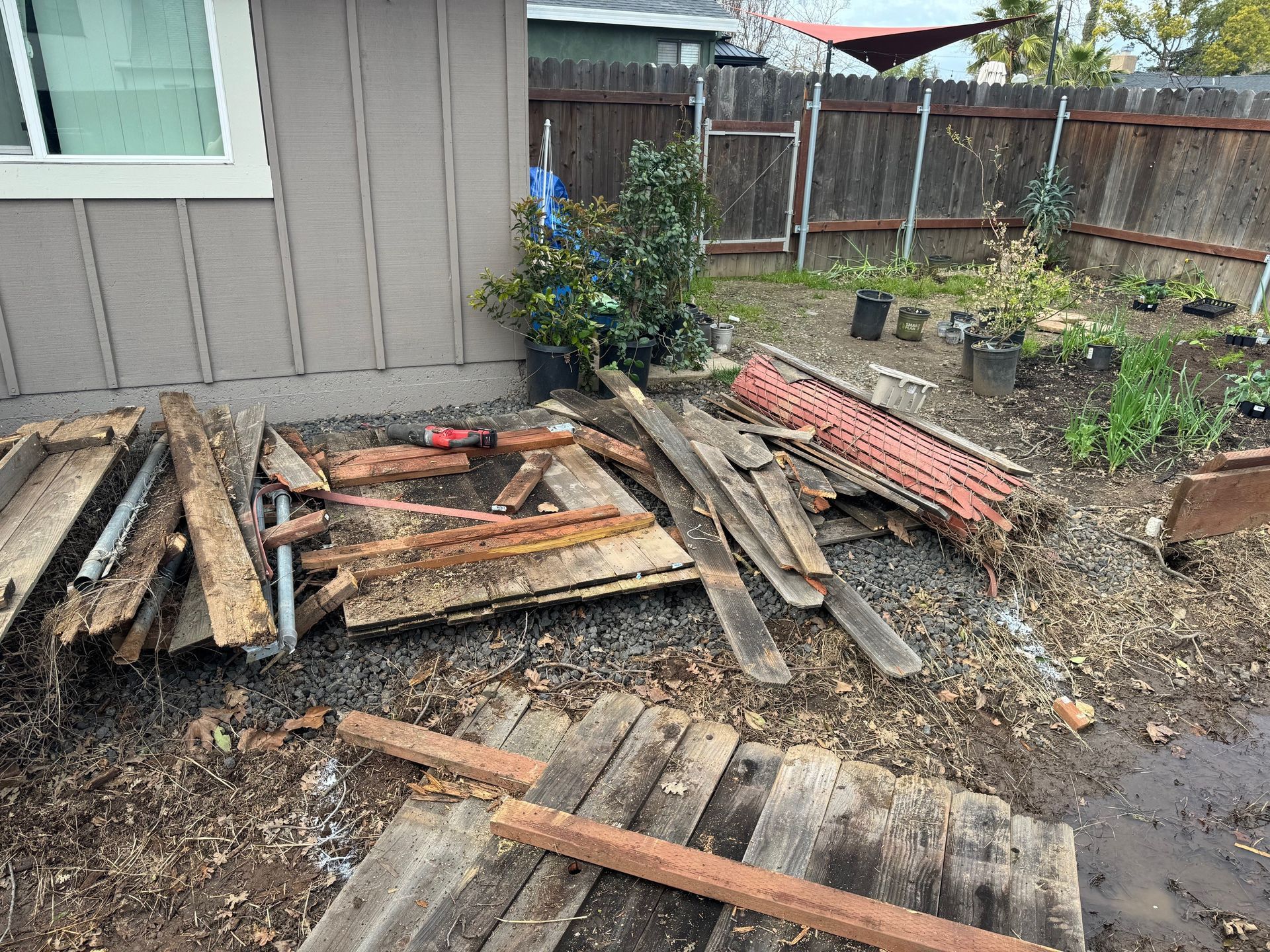 A pile of wood is sitting on the ground in front of a house.