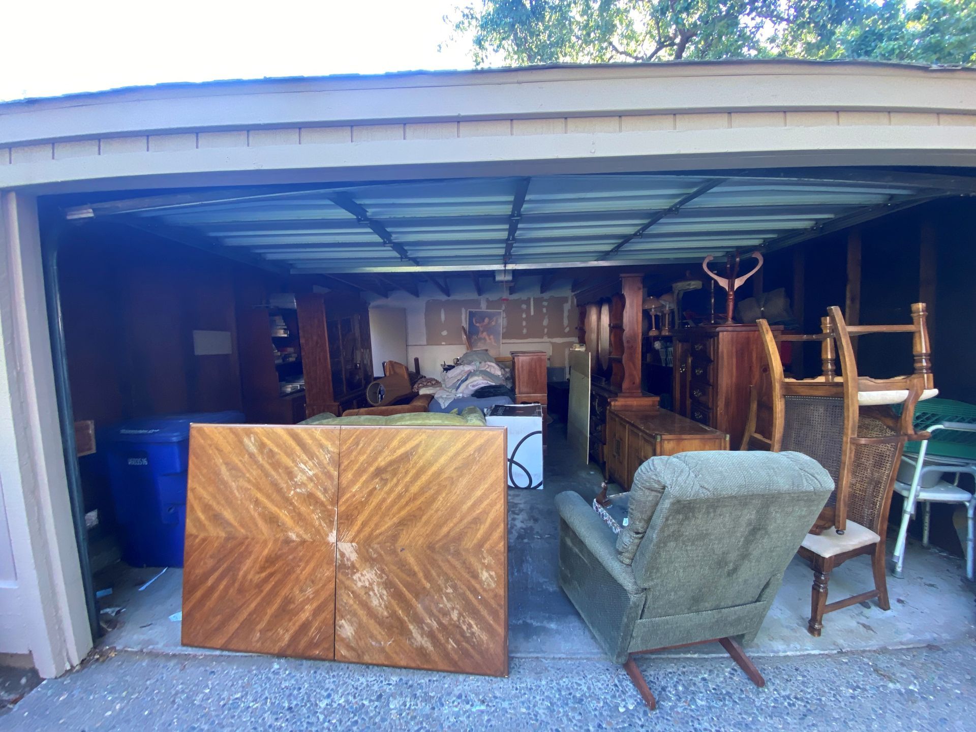 A garage filled with furniture and a blue trash can