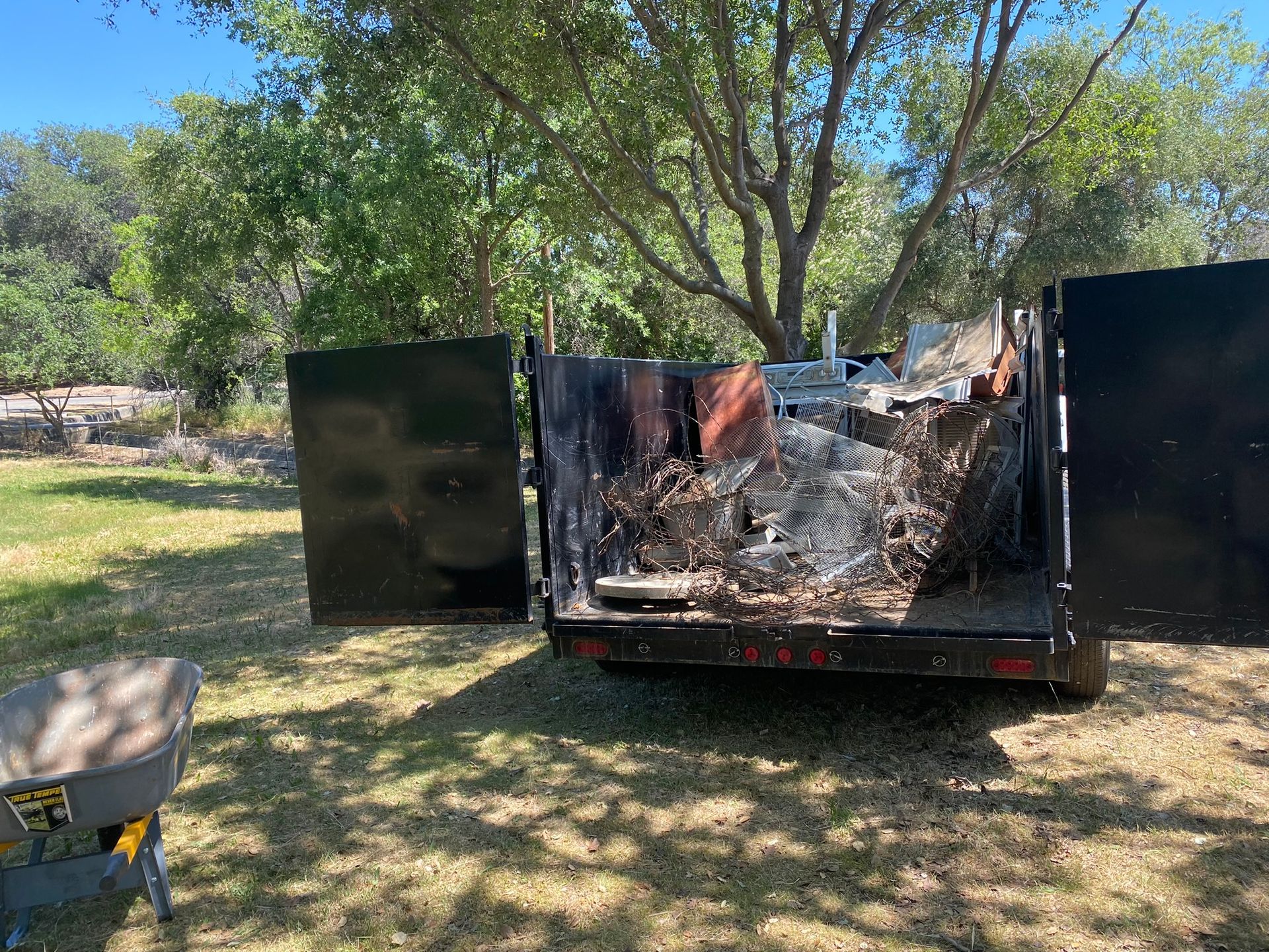 A dumpster is sitting in the grass with its doors open.