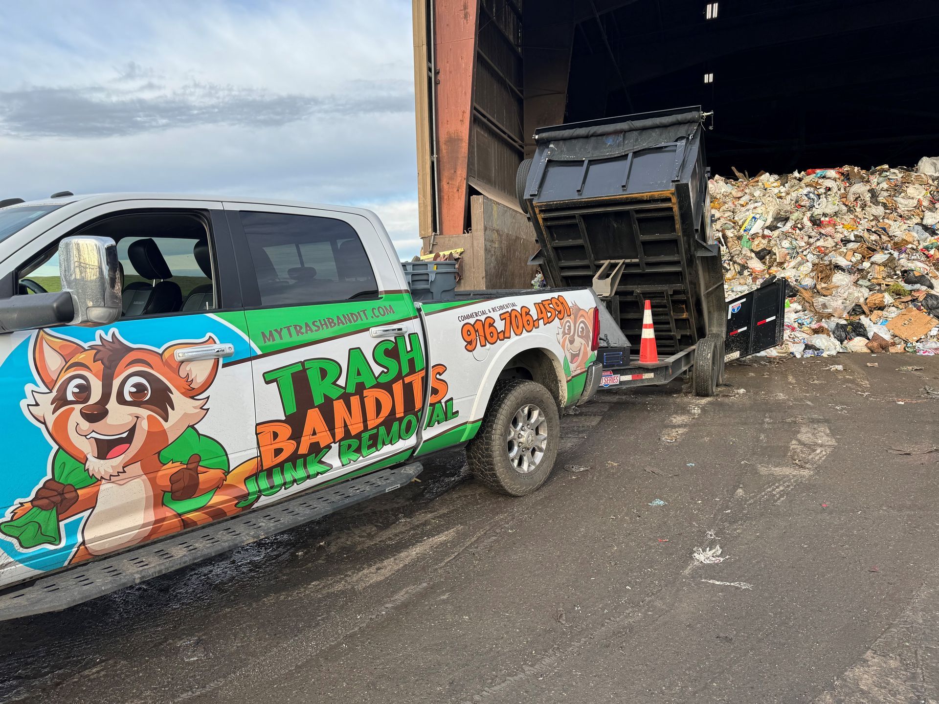 A trash bandits truck is parked in front of a pile of trash.