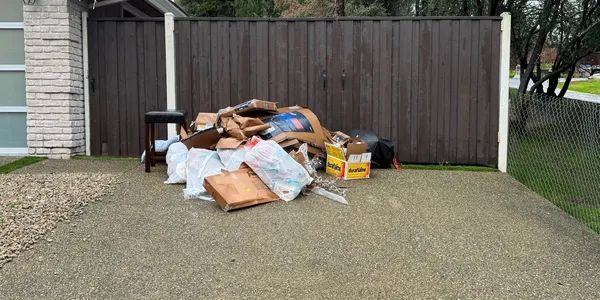 A pile of trash is sitting in a driveway in front of a house.