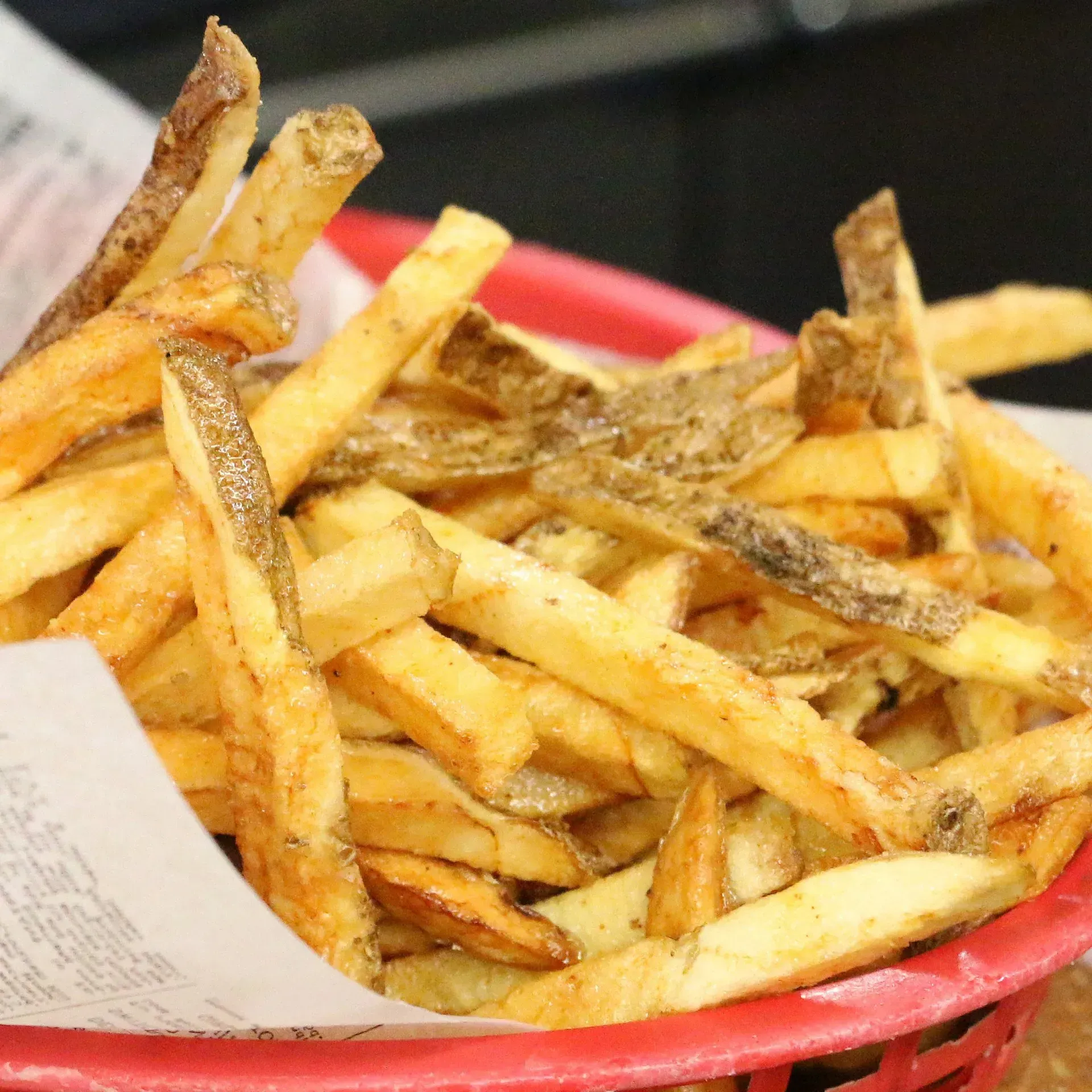 Golden french fries in a red basket lined with paper.