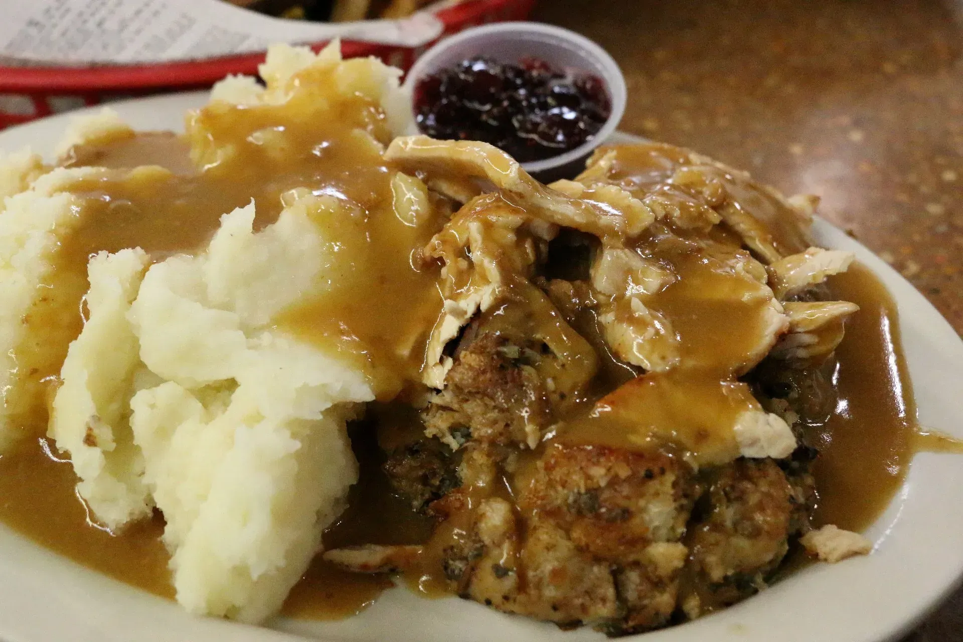 Plate of mashed potatoes, meatloaf, gravy, and cranberry sauce.