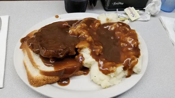 Plate of open-faced roast beef sandwich with mashed potatoes, covered in gravy.
