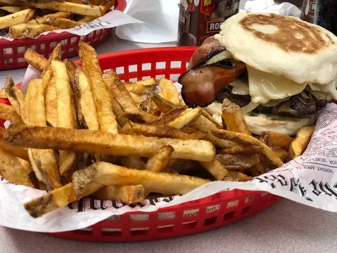 Basket of fries and a burger with bacon on an English muffin.
