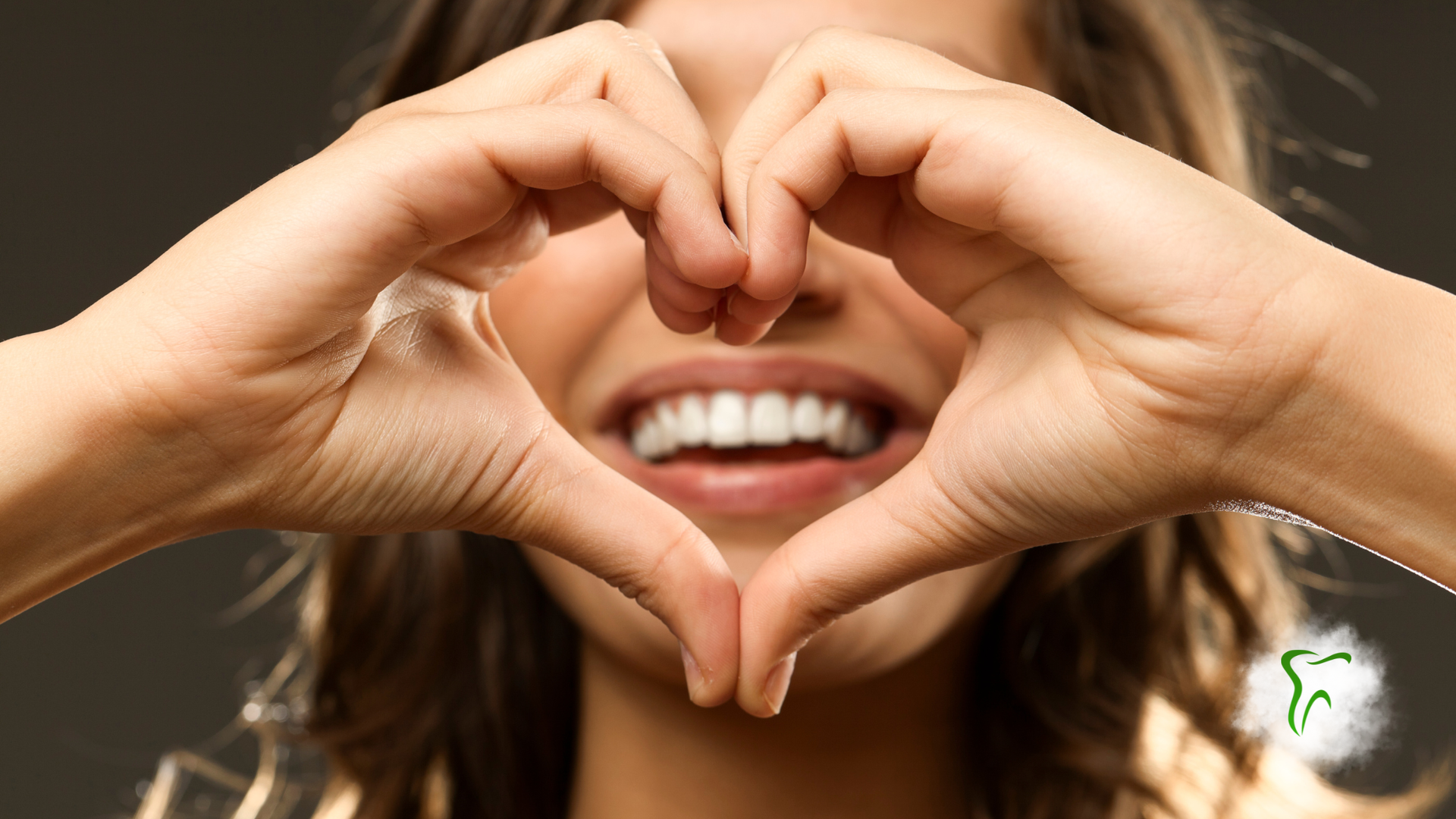 Woman smiling, forming a heart shape with hands over teeth.