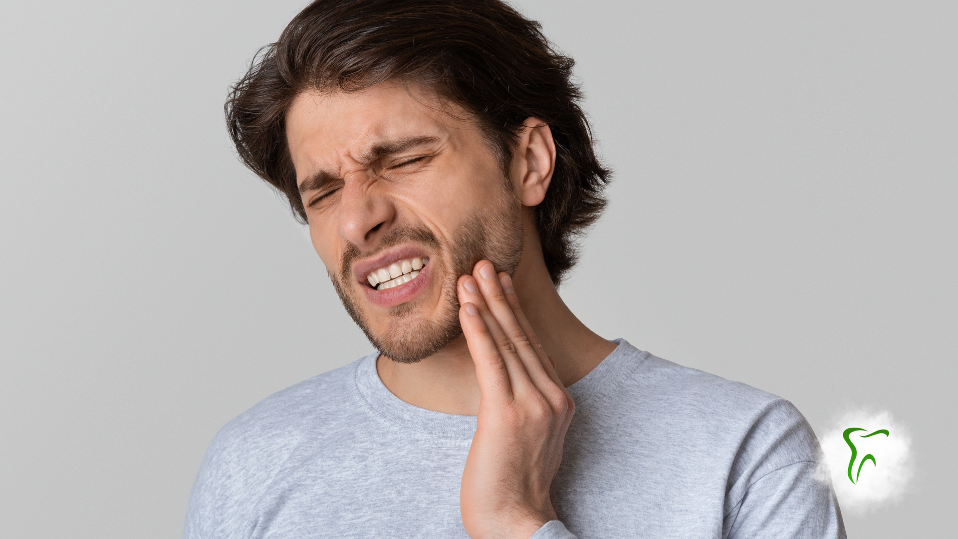 Man with pained expression, touching his jaw, possibly experiencing a toothache.