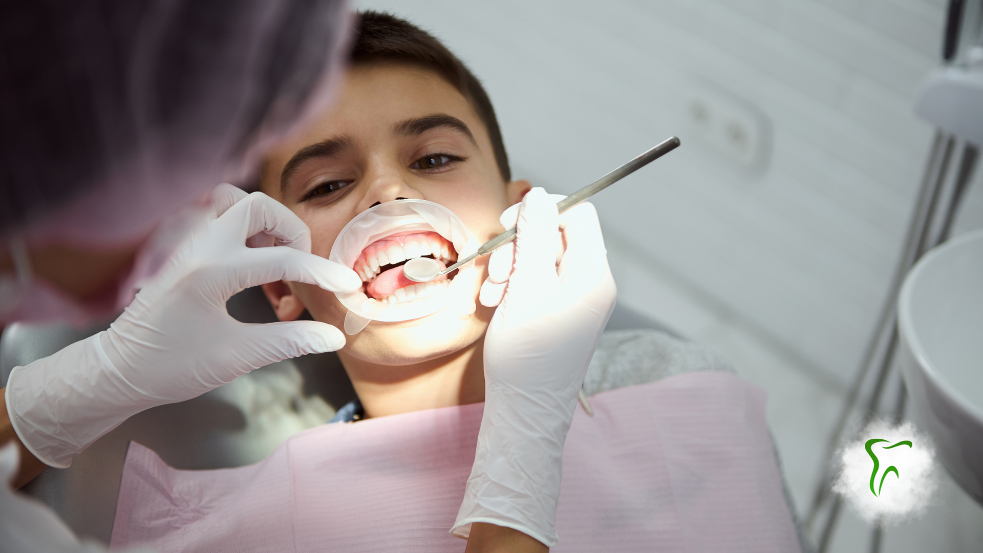 Boy at dentist with mouth open. Dentist using tools in mouth.