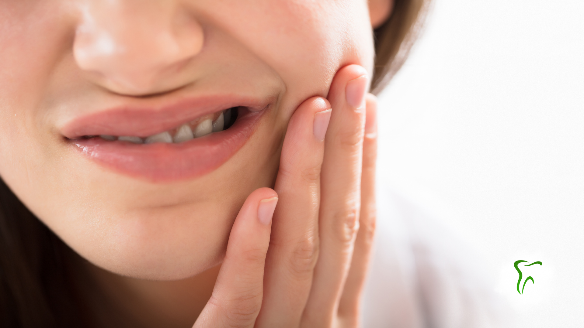 Woman holding face in pain, eyes closed, white tank top, light background.