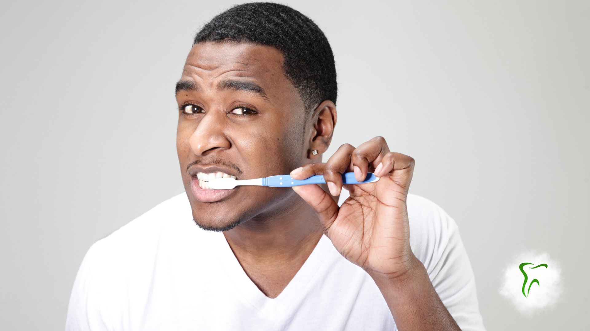 Woman brushing teeth with a green toothbrush, mouth open, white foam visible.