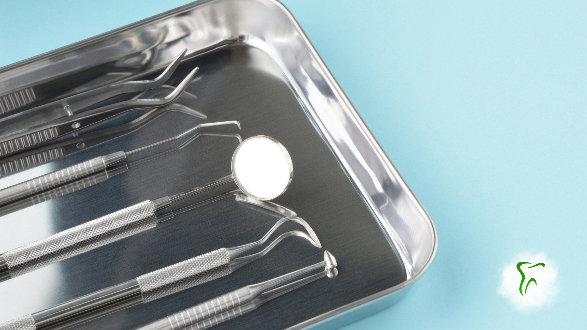 Dental tools on a metal tray; the tools include picks and a small mirror, on a light blue surface.