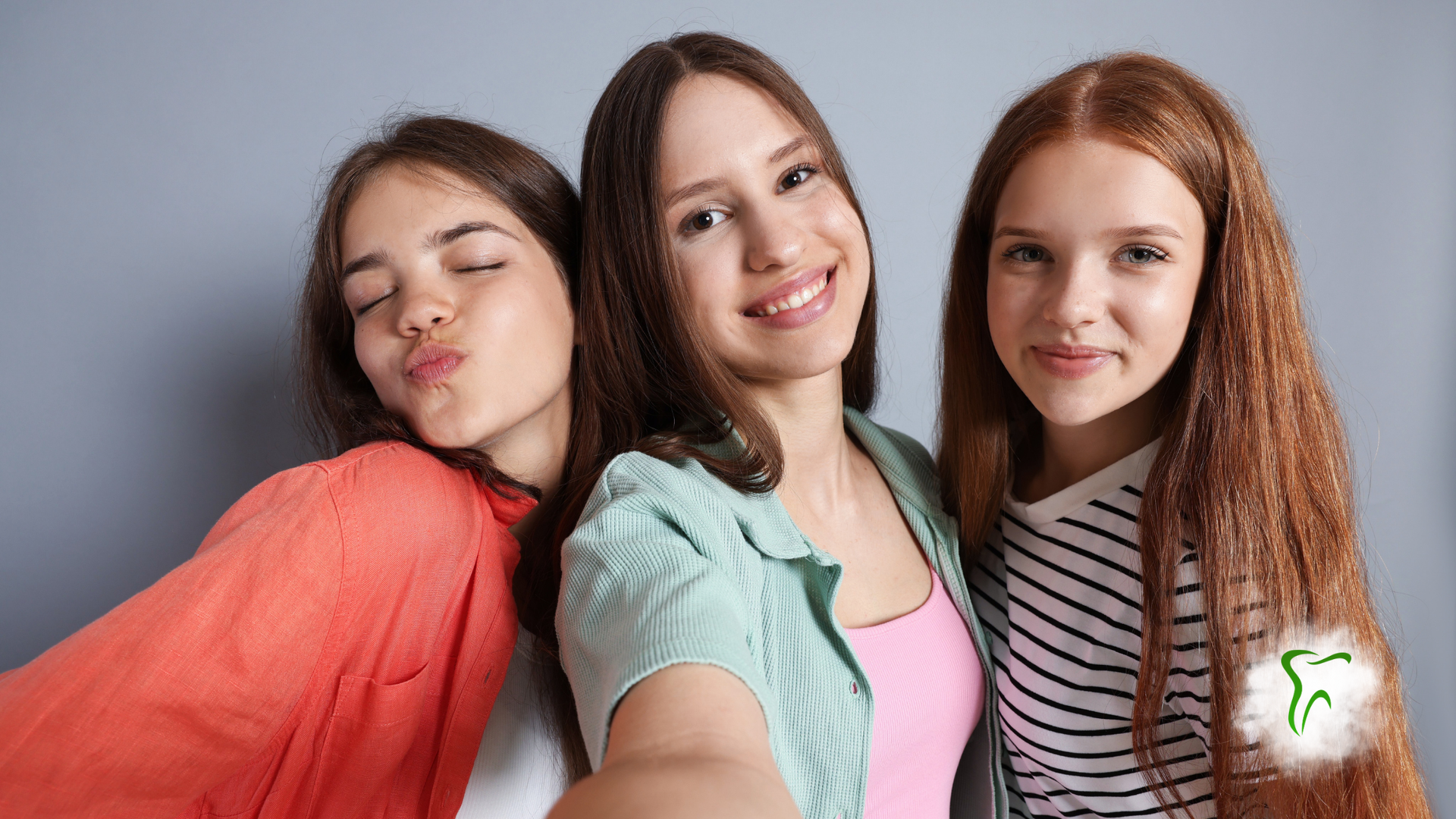 Four smiling people huddle together under a blue sky, arms around each other, looking down.