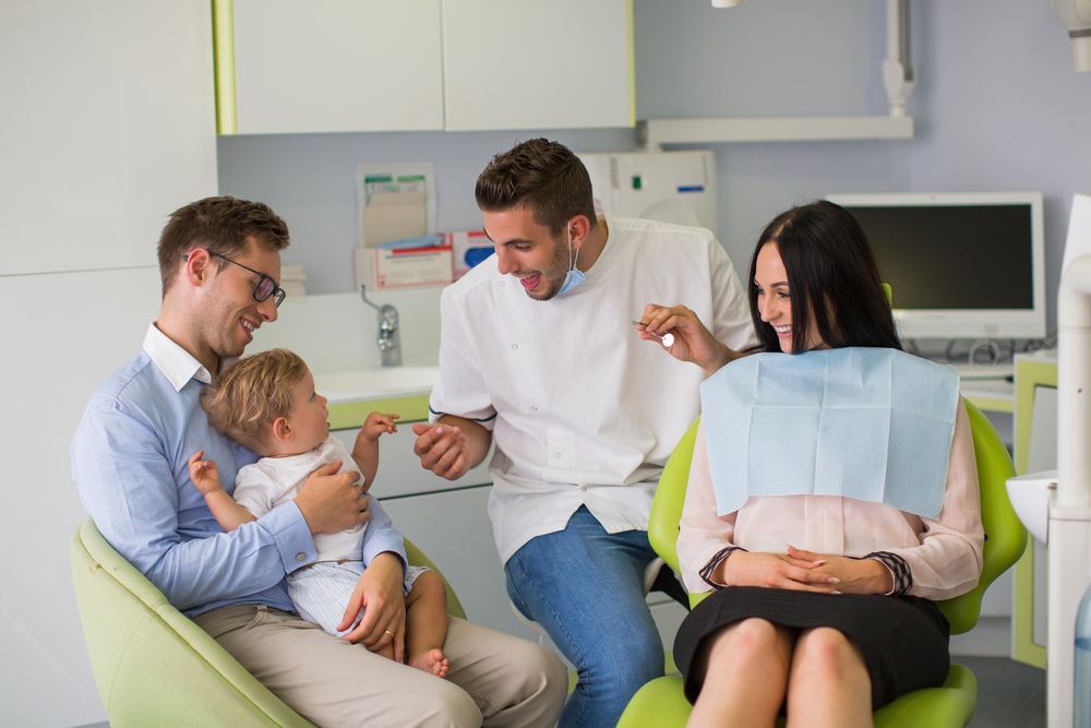 A group of people are sitting in a dental chair talking to a dentist.