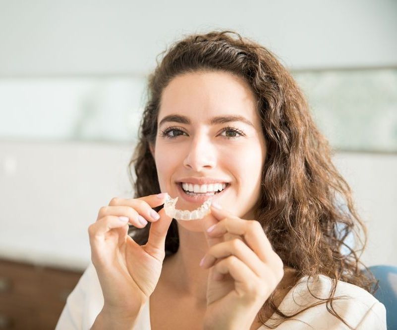 A woman holding Invisalign®.