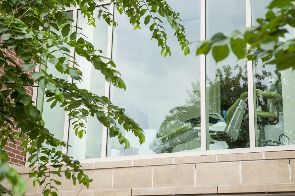 A dental chair is reflected in the window of a dental office.