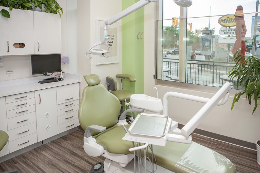 A dental office with a green dental chair and a window.