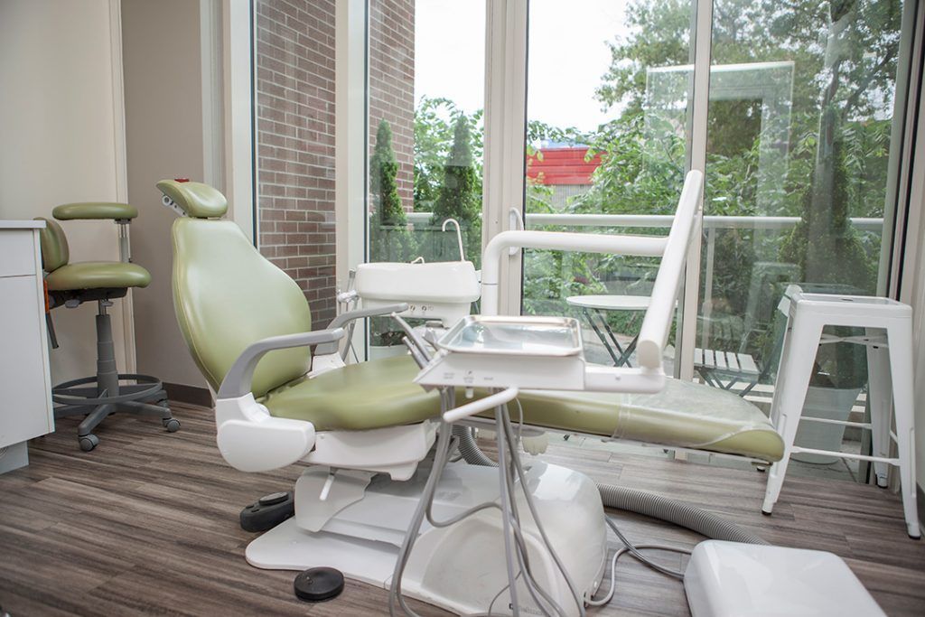 A dental office with a green dental chair and a large window.