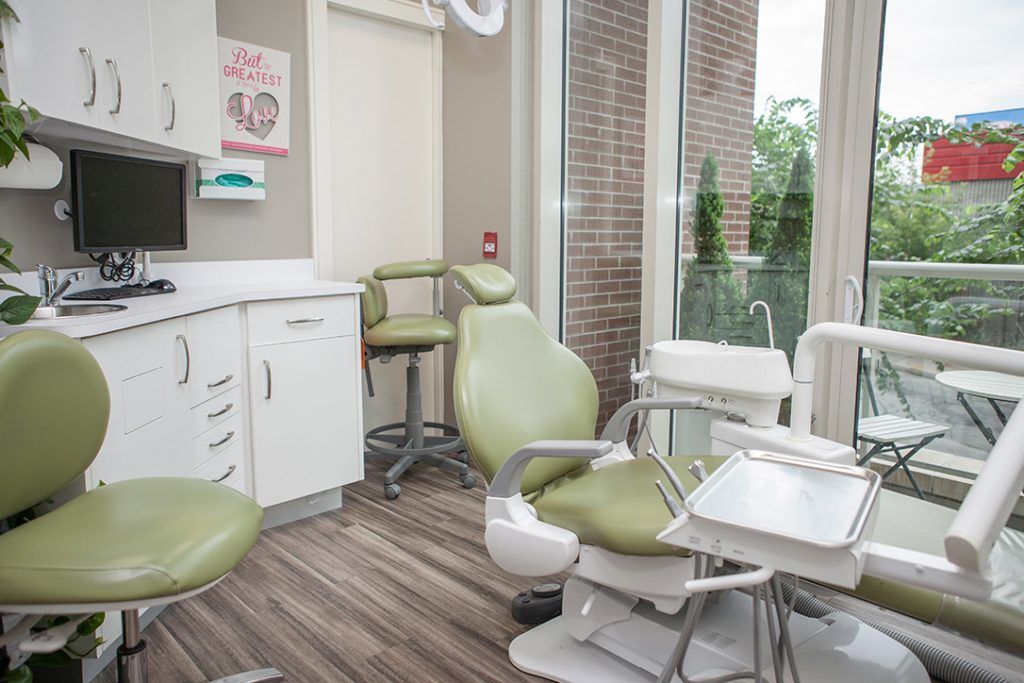 A dental office with green chairs and a large window.