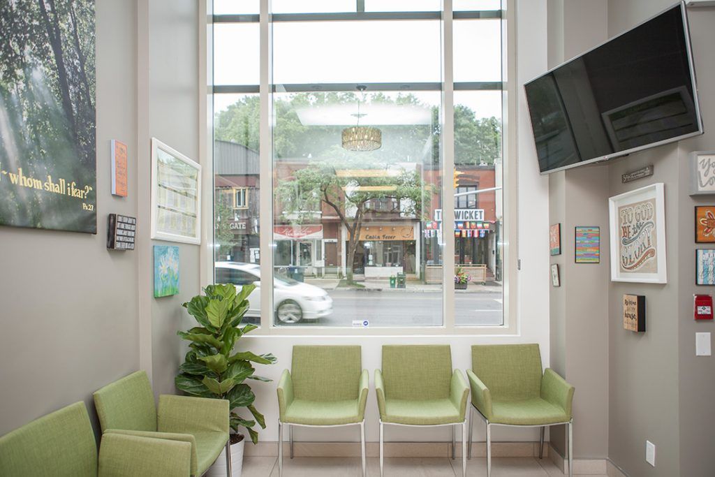 A waiting room with green chairs and a large window.