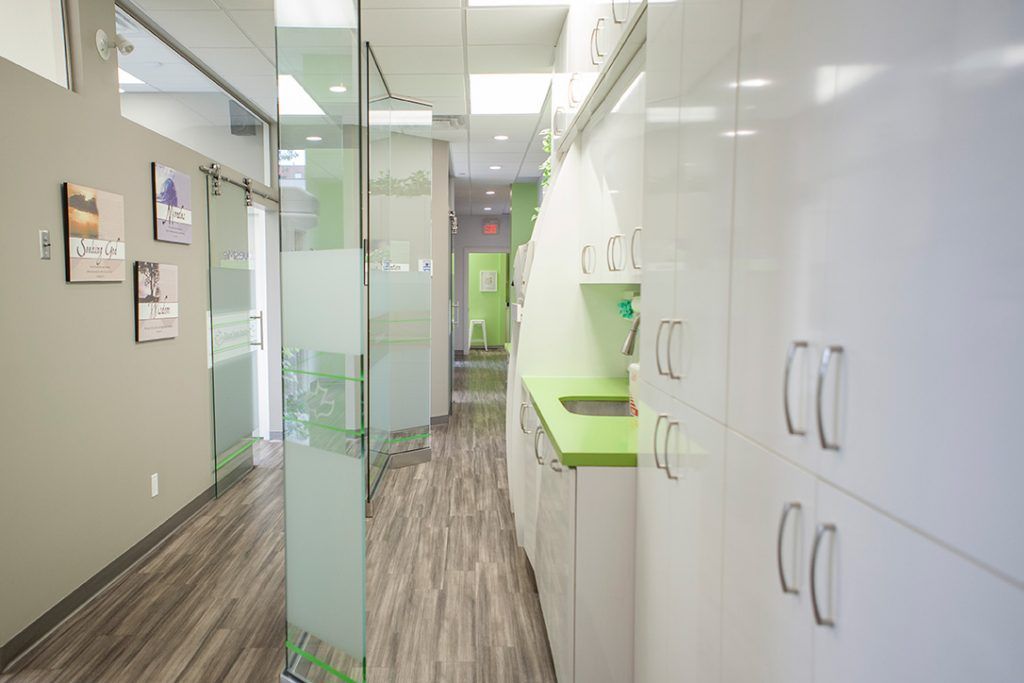 A long hallway with white cabinets and green counter tops in a dental office.
