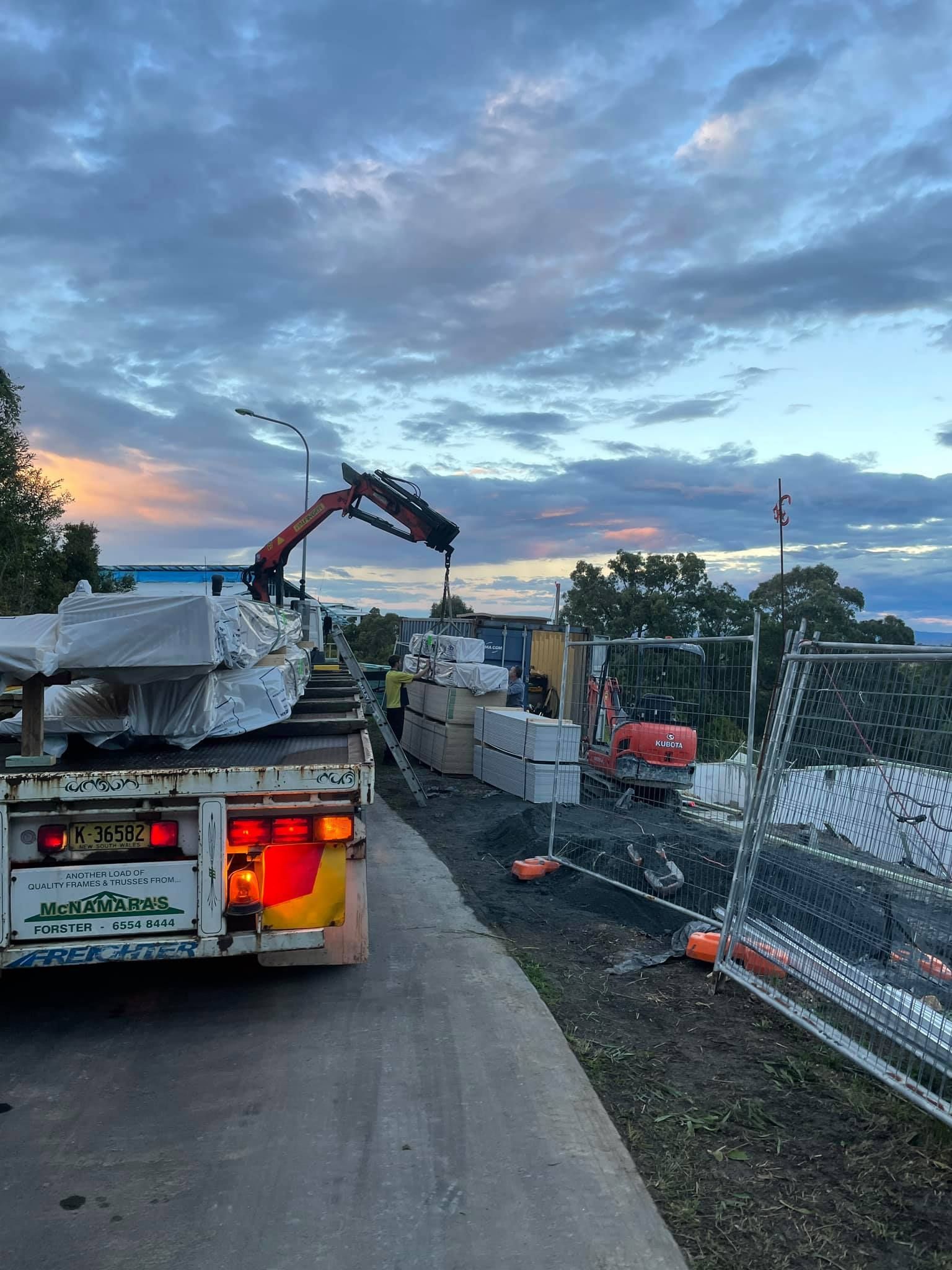 A Truck With a Crane Unloading Building Materials — McNamara's Frames & Trusses In Forster, NSW