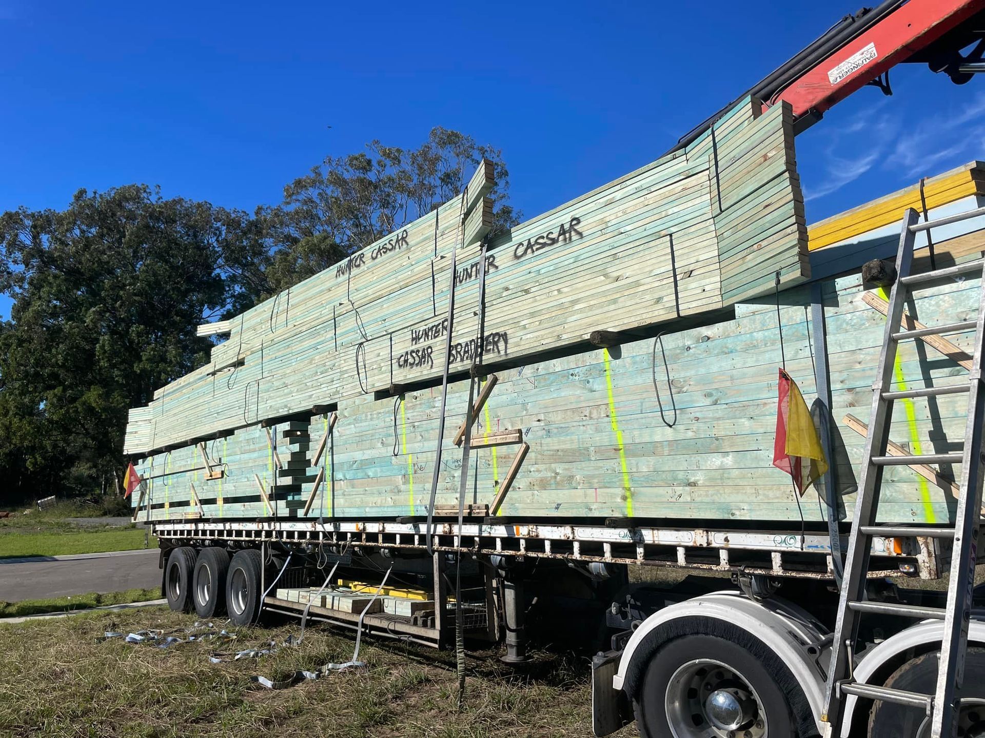 Truck Loaded With Lumber Under a Blue Sky; Crane Arm and Ladder Visible — McNamara's Frames & Trusses In Newcastle, NSW