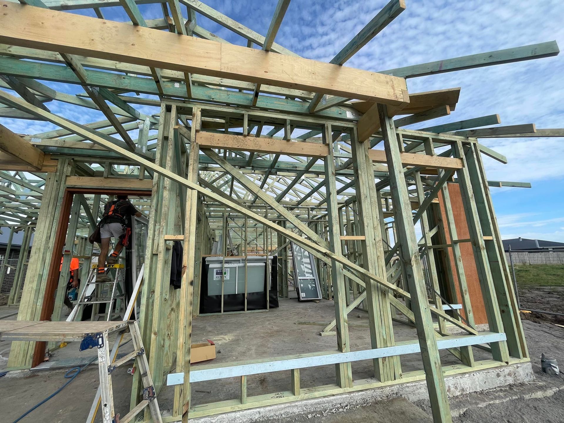 Wooden House Frame Under Construction; a Worker on a Ladder — McNamara's Frames & Trusses In Hunter Valley, NSW