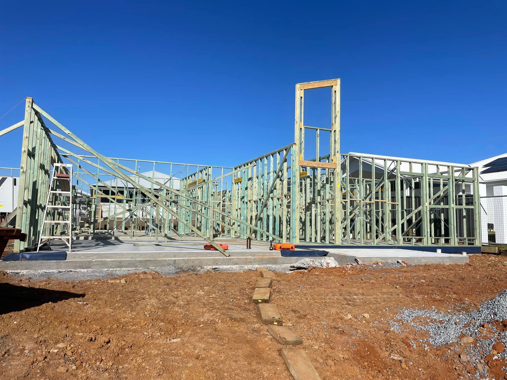 Wooden Frame of a House Under Construction Against a Clear Blue Sky — McNamara's Frames & Trusses In Woy Woy, NSW