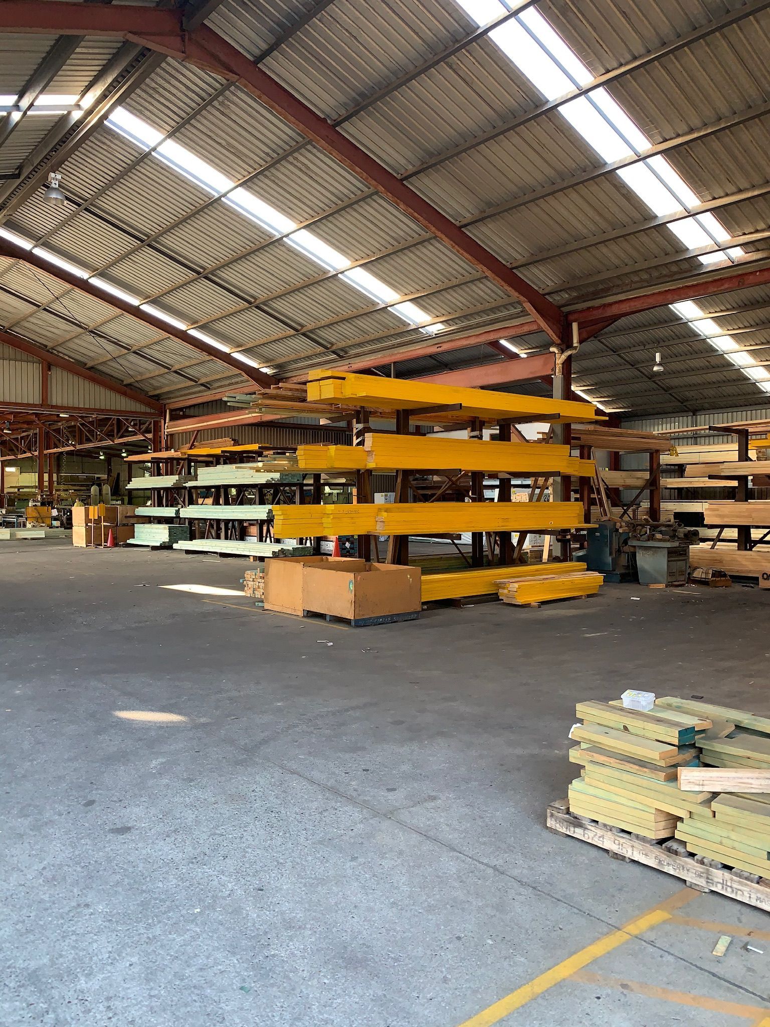 Warehouse Interior With Yellow Cantilever Racking Holding Lumber — McNamara's Frames & Trusses In Forster, NSW