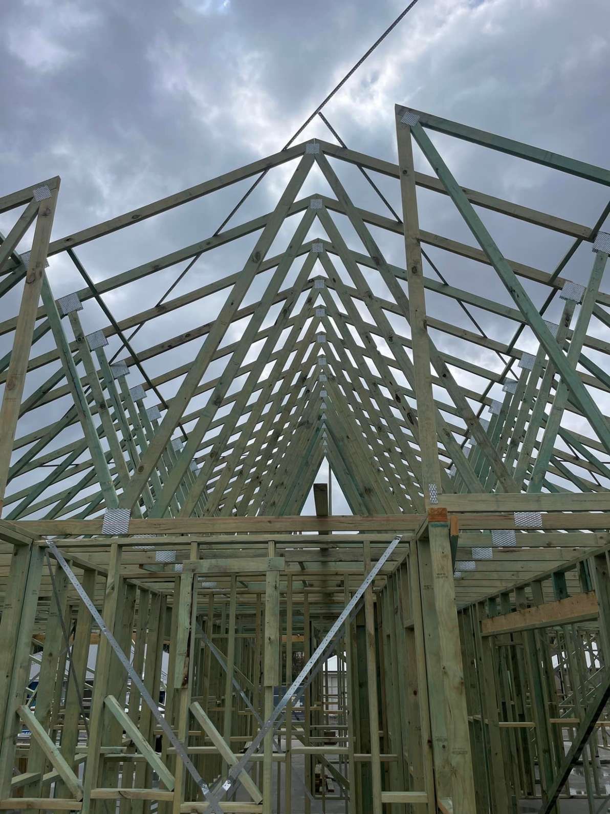 Wooden Roof Trusses Being Built on a Framed House Under a Cloudy Sky — McNamara's Frames & Trusses In Mid North Coast, NSW