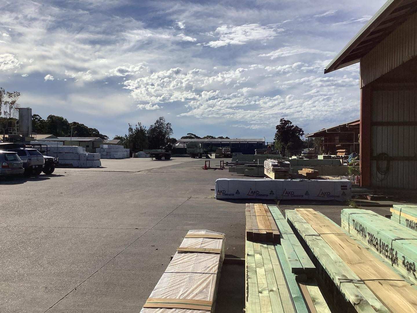 Lumber Yard With Stacks of Wood, Parked Vehicles, and a Cloudy Sky — McNamara's Frames & Trusses In Terrigal, NSW