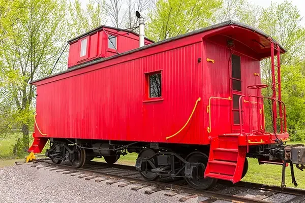 Red caboose on train tracks, with a cupola on top.