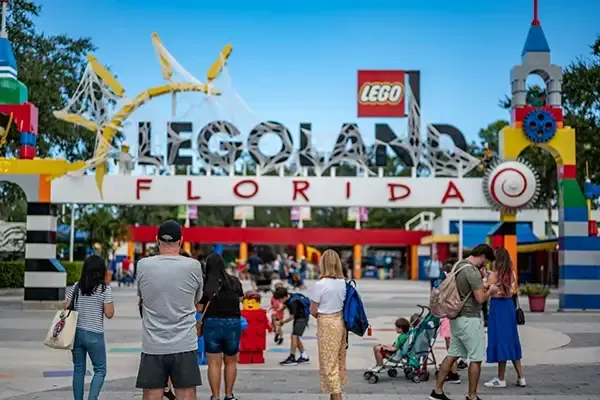 Legoland Florida entrance sign with colorful archway, people entering and exiting.