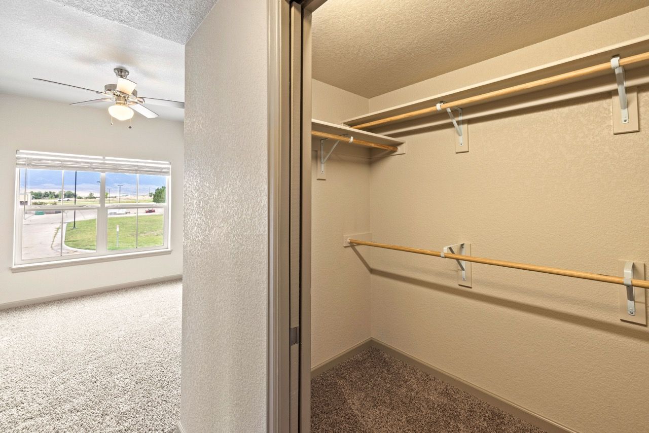 Walk-in closet with hanging rods and shelves in a beige apartment.