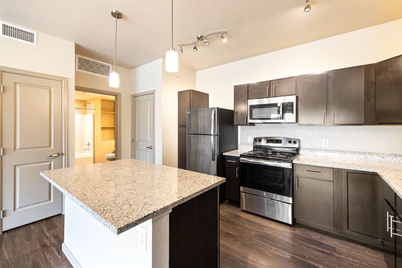 Kitchen in an apartment with granite countertops, stainless steel appliances, and a center island.