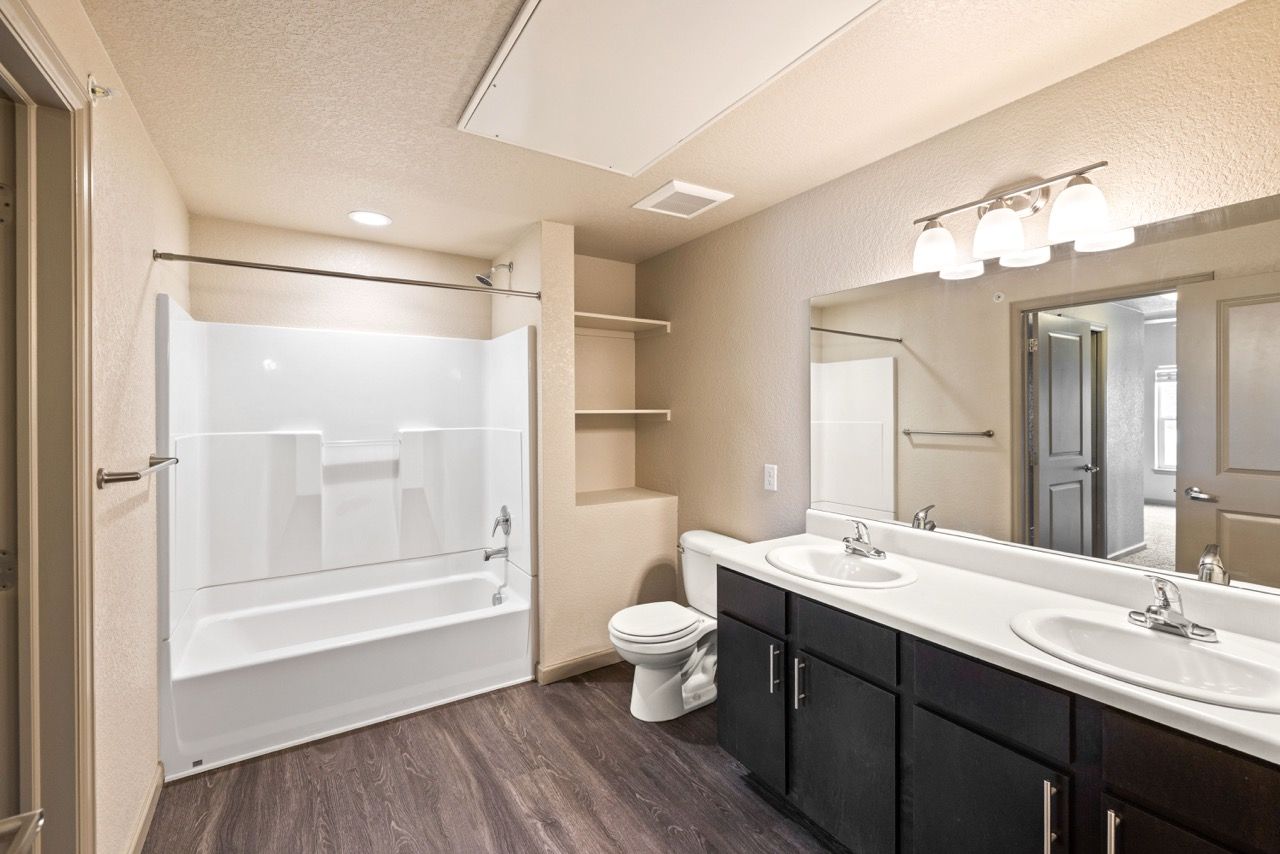 Bathroom in an apartment featuring a double-sink vanity, toilet, and a tub/shower combo.
