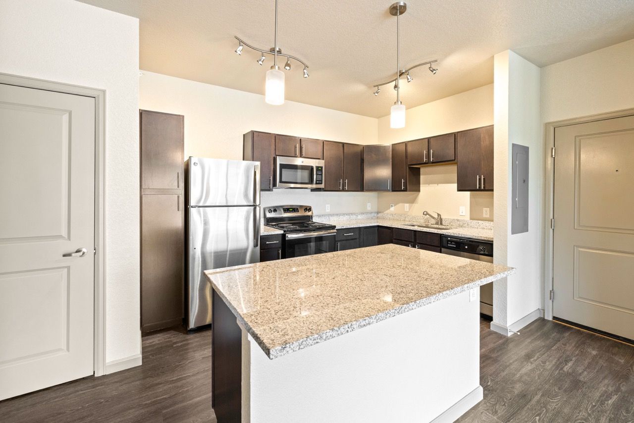 Modern kitchen with granite countertops, stainless steel appliances, and an island.