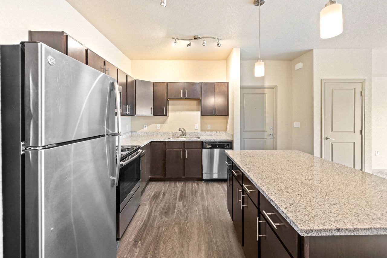 Modern kitchen with granite countertops, dark wood cabinets, and stainless steel appliances.
