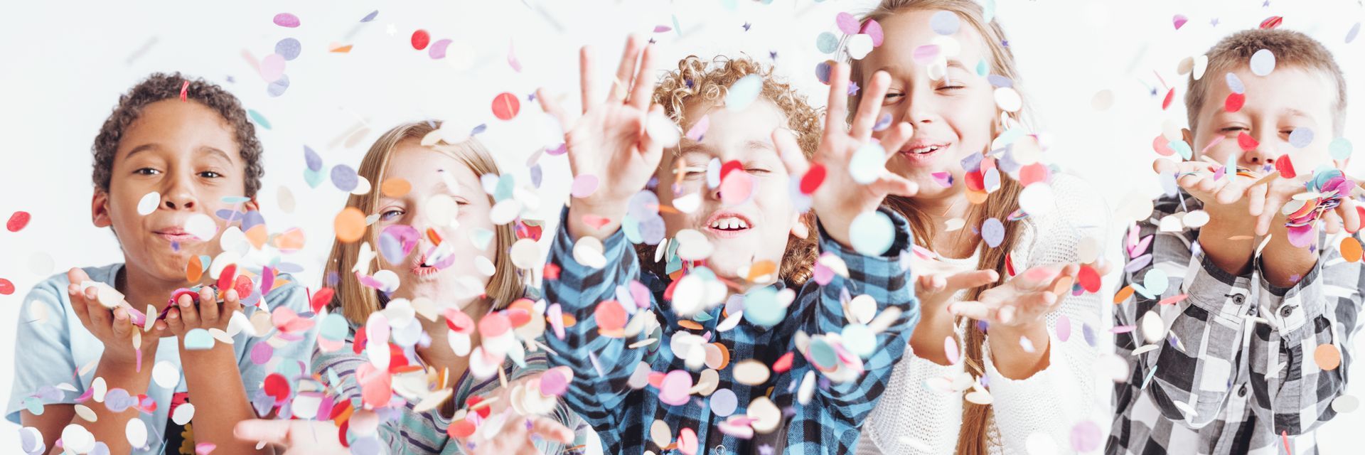 Children laughing and throwing colorful confetti in a bright celebration scene