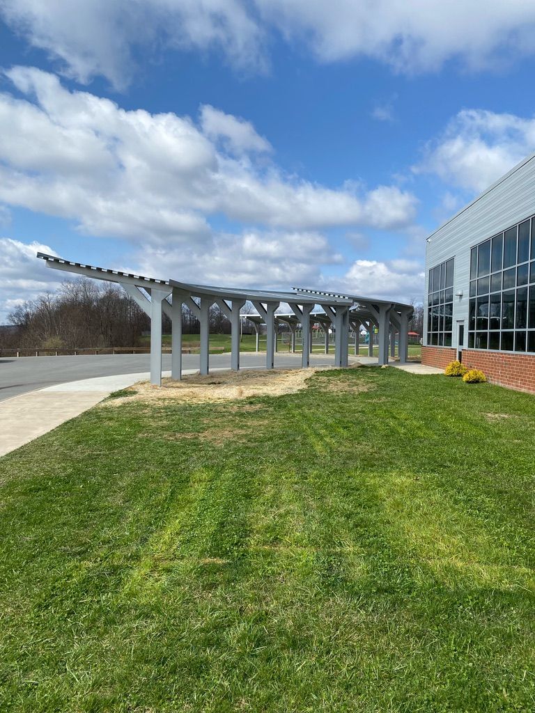 Exterior of a building with a metal awning and a walkway. Cloudy sky above.