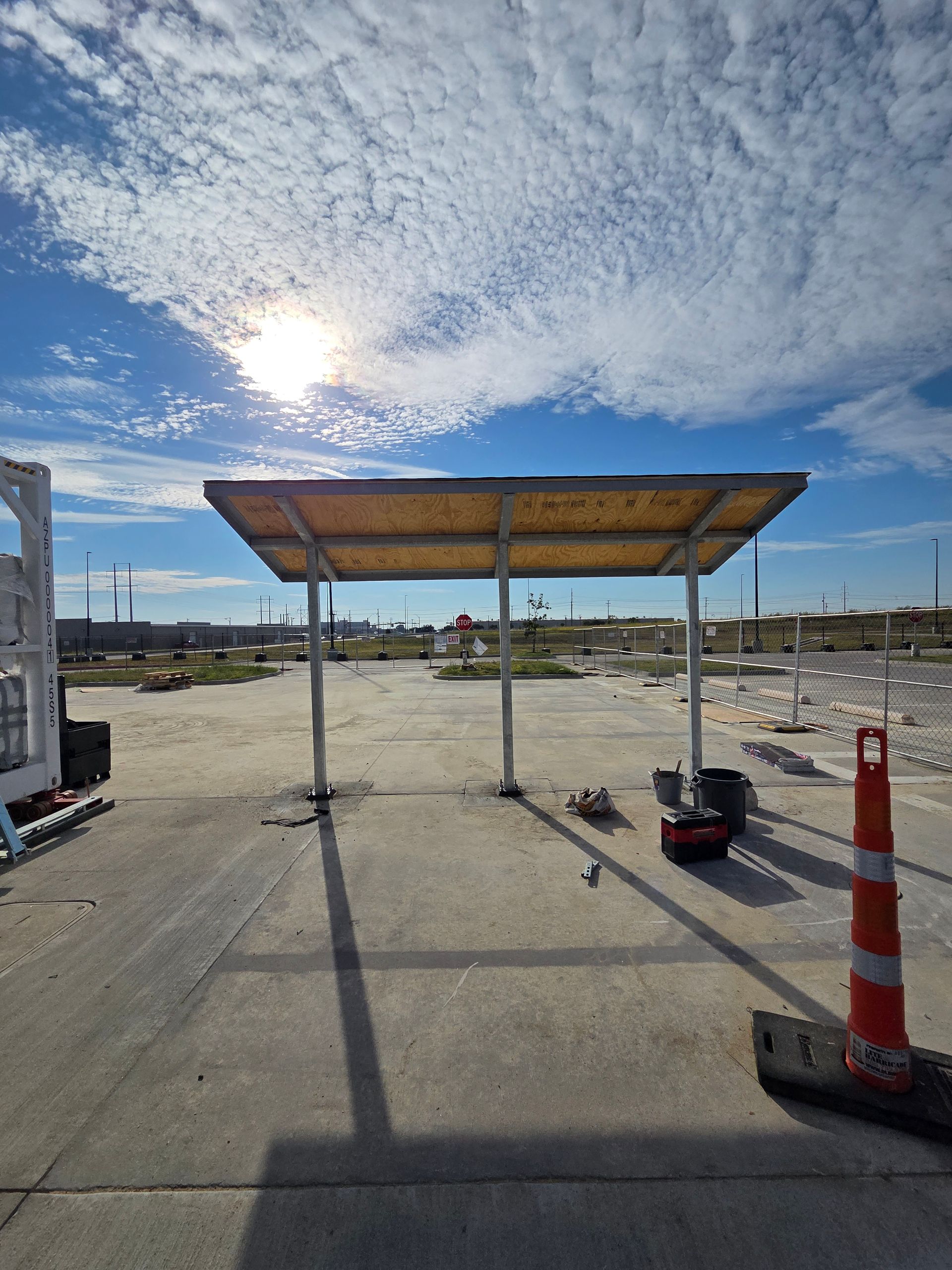 Exterior of a building with a metal awning and a walkway. Cloudy sky above.