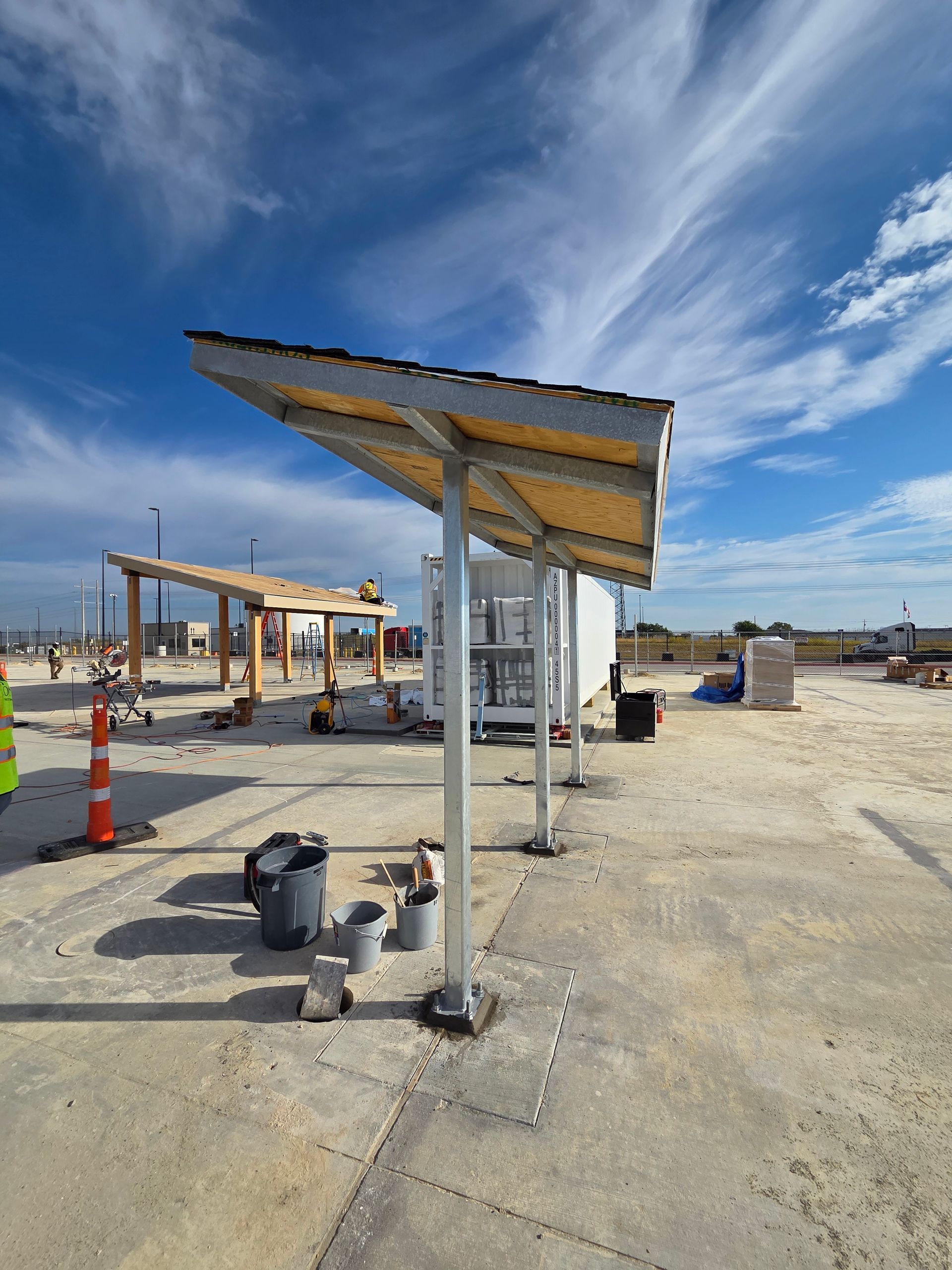 Exterior of a building with a metal awning and a walkway. Cloudy sky above.