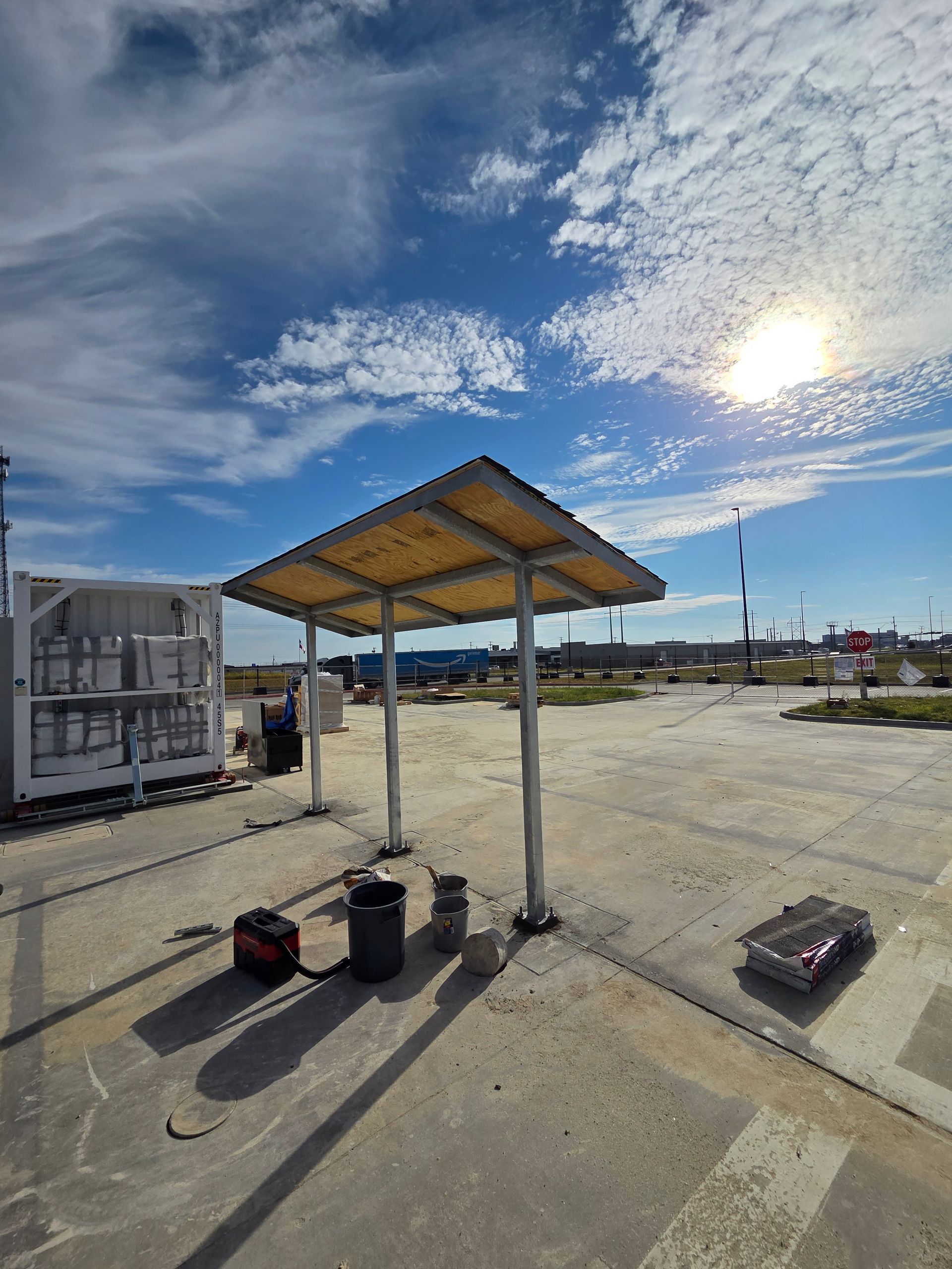 Exterior of a building with a metal awning and a walkway. Cloudy sky above.