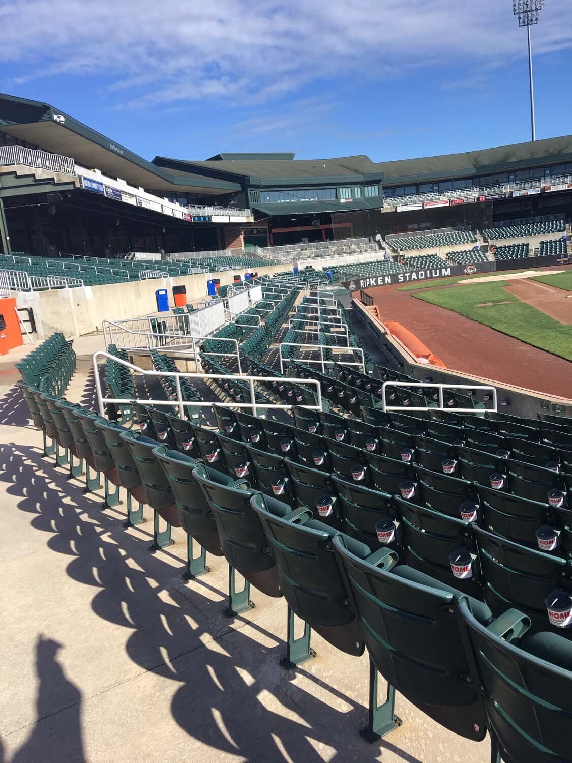 Empty baseball stadium with green seats and a blue sky.