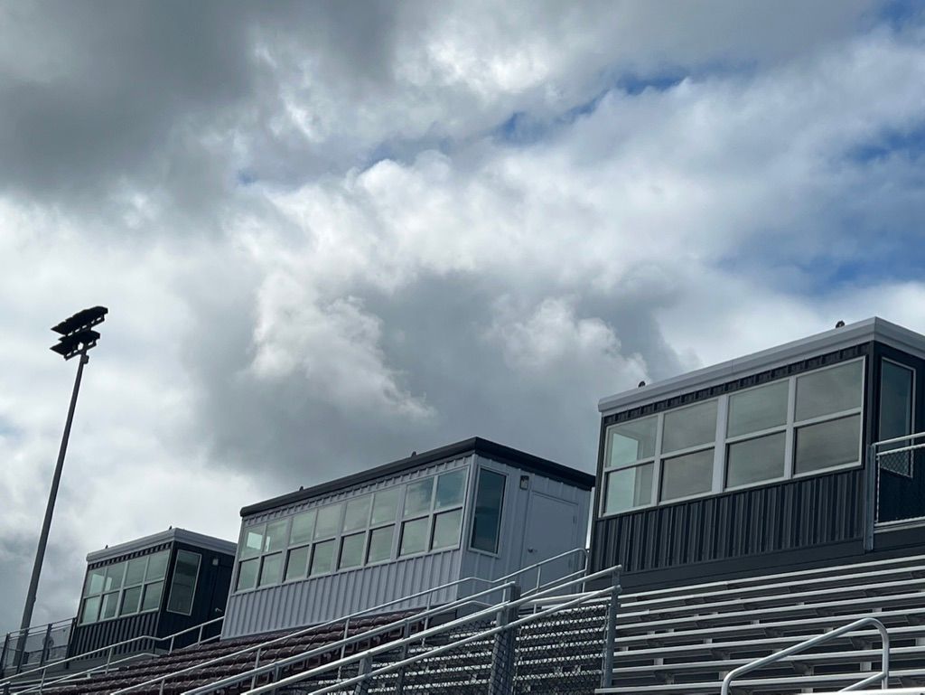 Football stadium press boxes under a cloudy sky.