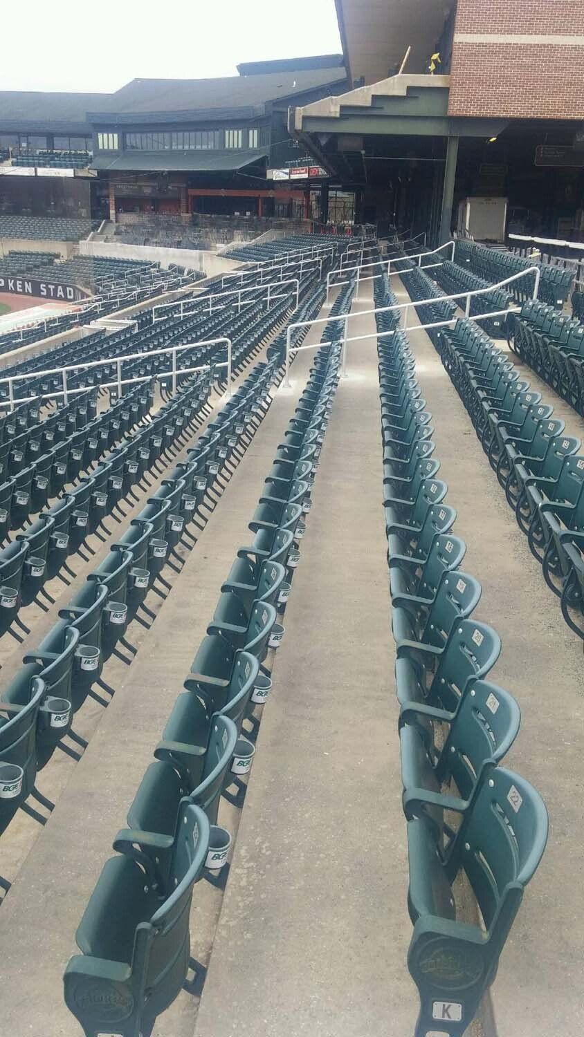 Rows of empty green stadium seats, concrete floor, buildings in the background.