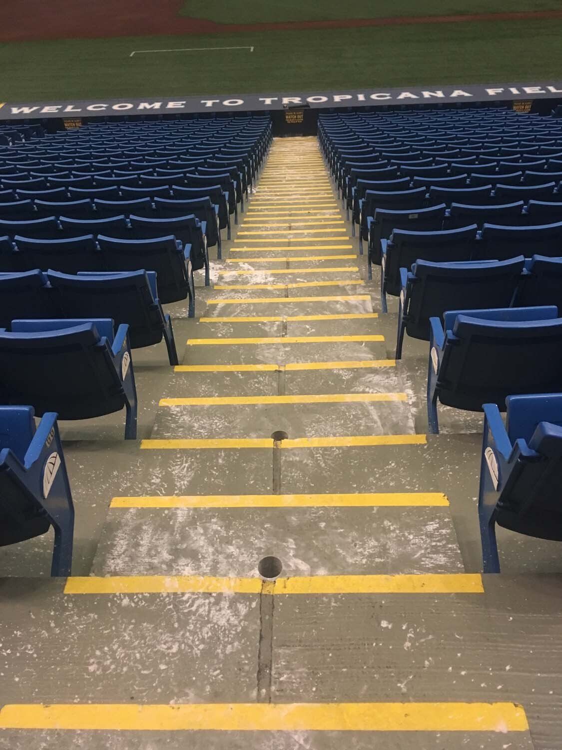 Empty stadium seating with yellow-marked steps and dark blue chairs; 