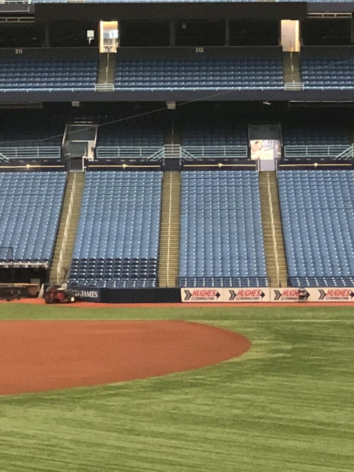 Baseball stadium with rows of blue seats, field, and warning track.