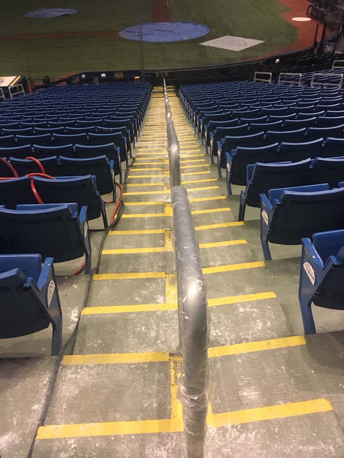Stairway with handrail in empty baseball stadium, blue seating.