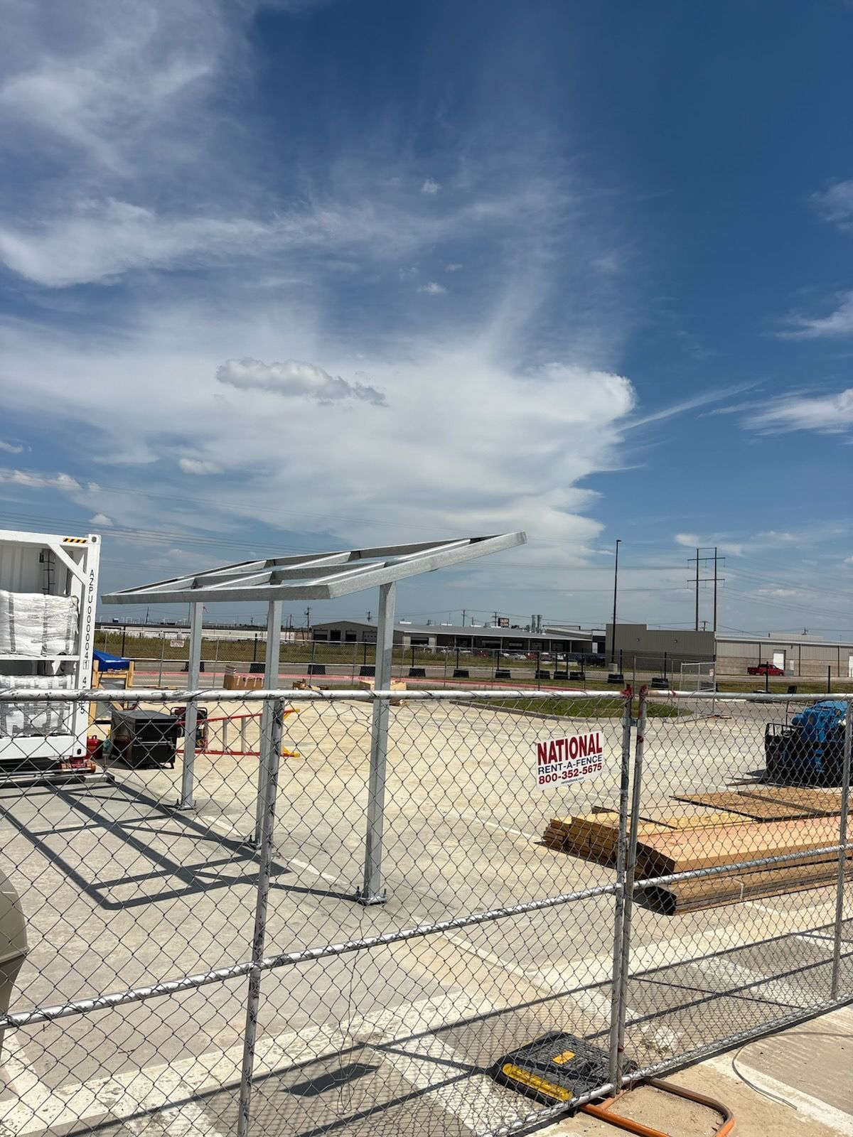 Exterior of a building with a metal awning and a walkway. Cloudy sky above.